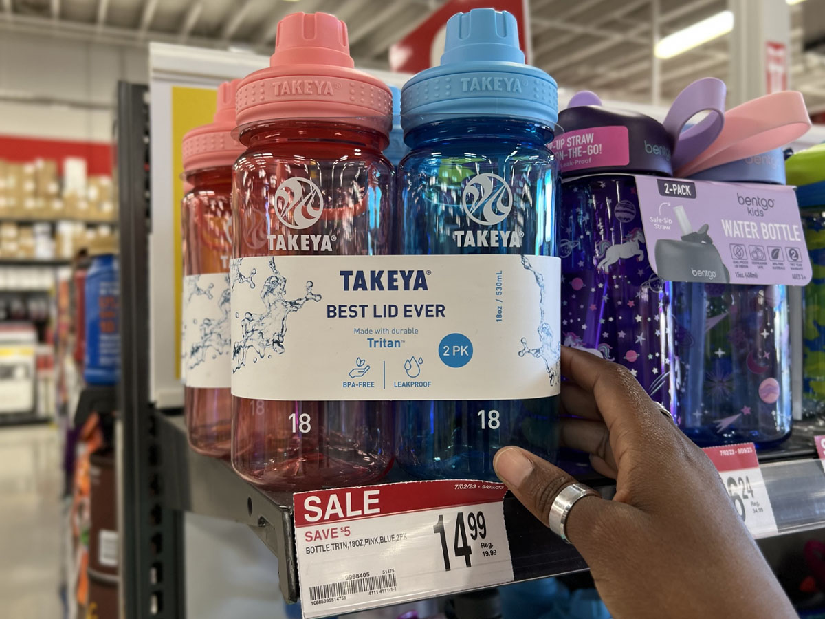 hand holding pink and blue water bottle pack on shelf