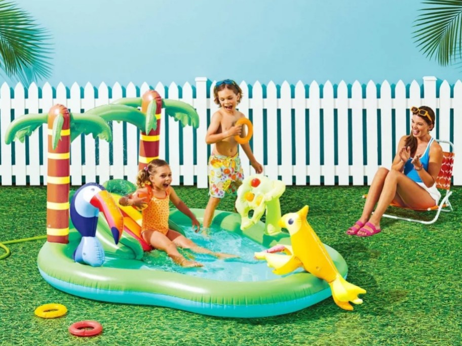 kids playing on an inflatable jungle themed water splash pad pool