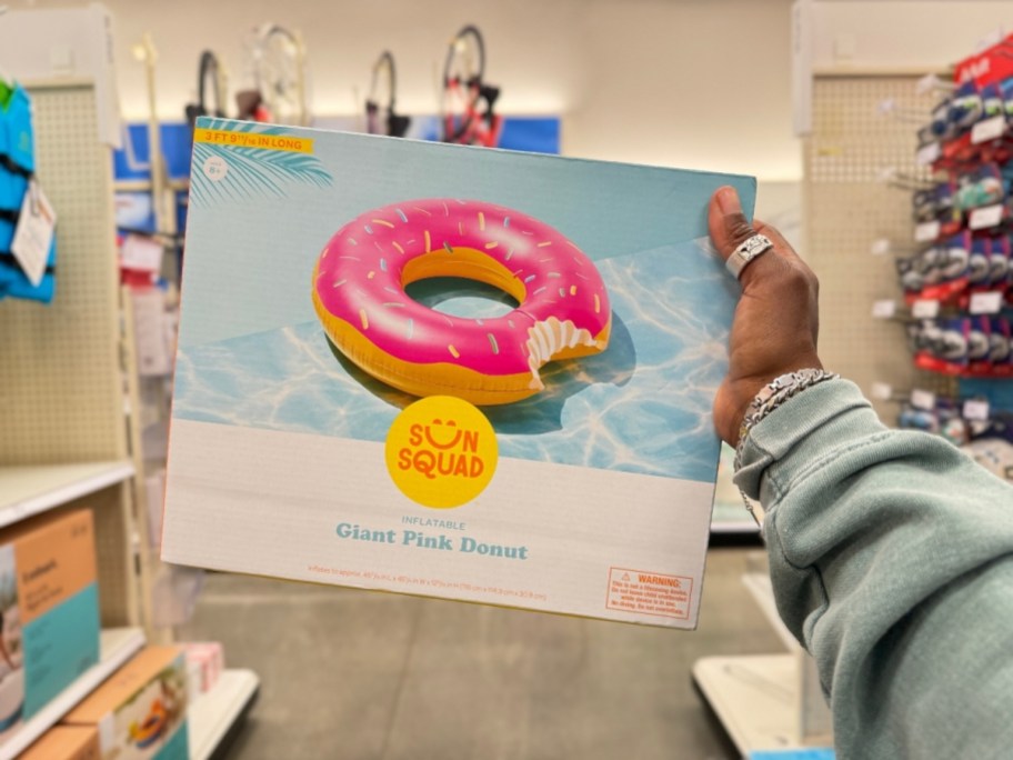 hand holding a pink donut pool float in the package