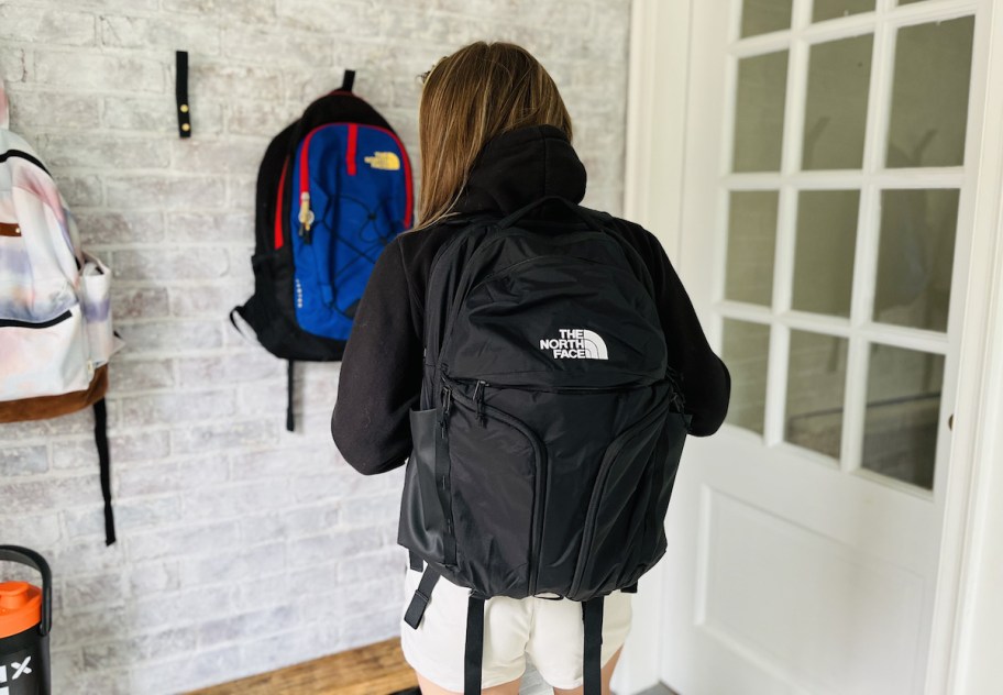 woman wearing black the north face bookbag in mud room