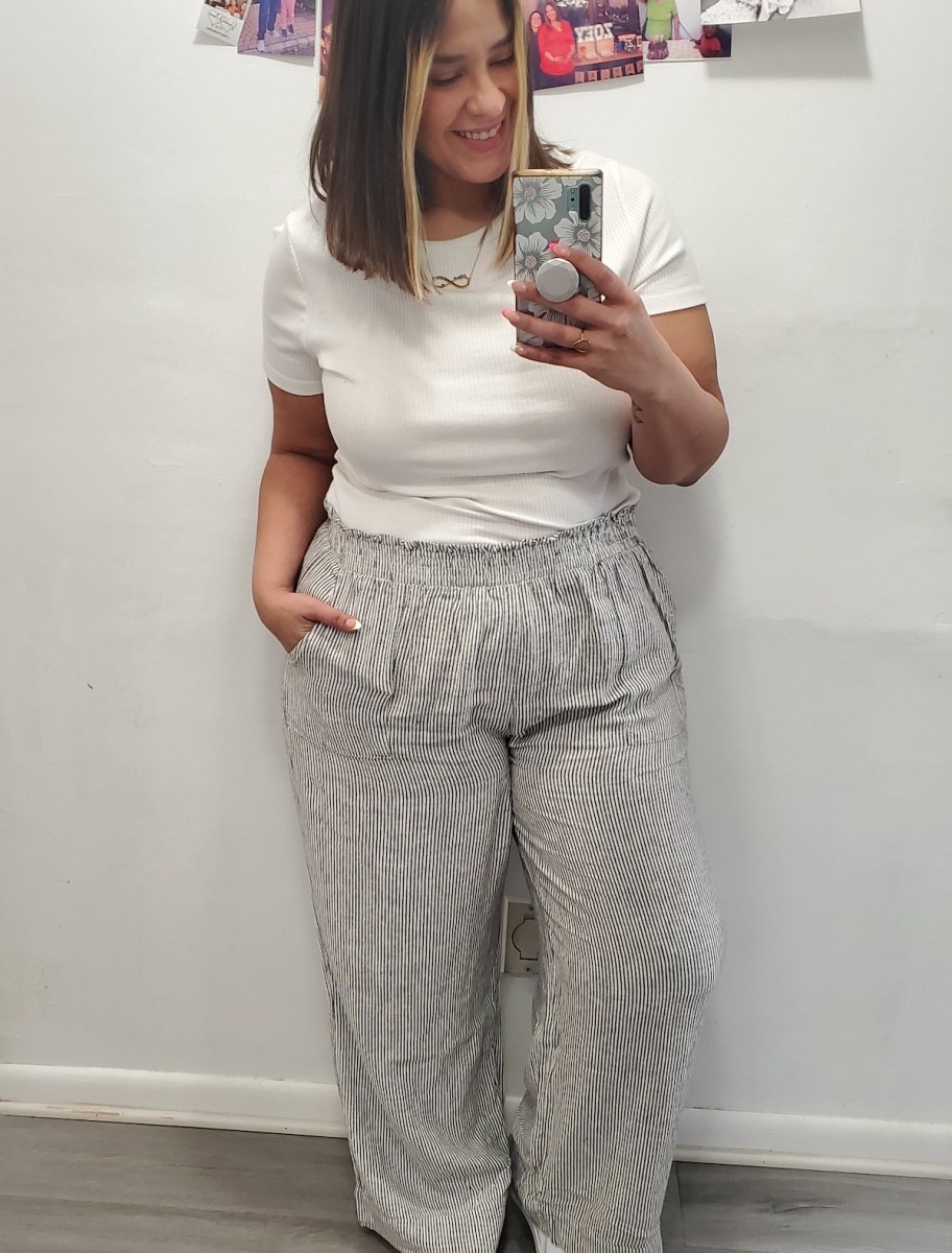 woman taking mirror selfie wearing linen pants and white top