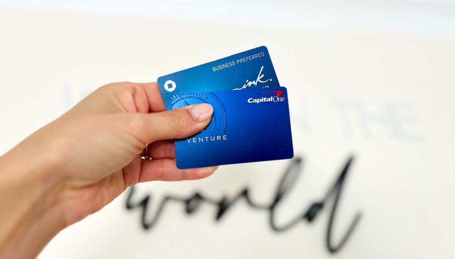 hand holding blue credit cards in front of world sign