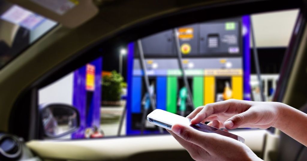 person holding phone in car outside of gas station