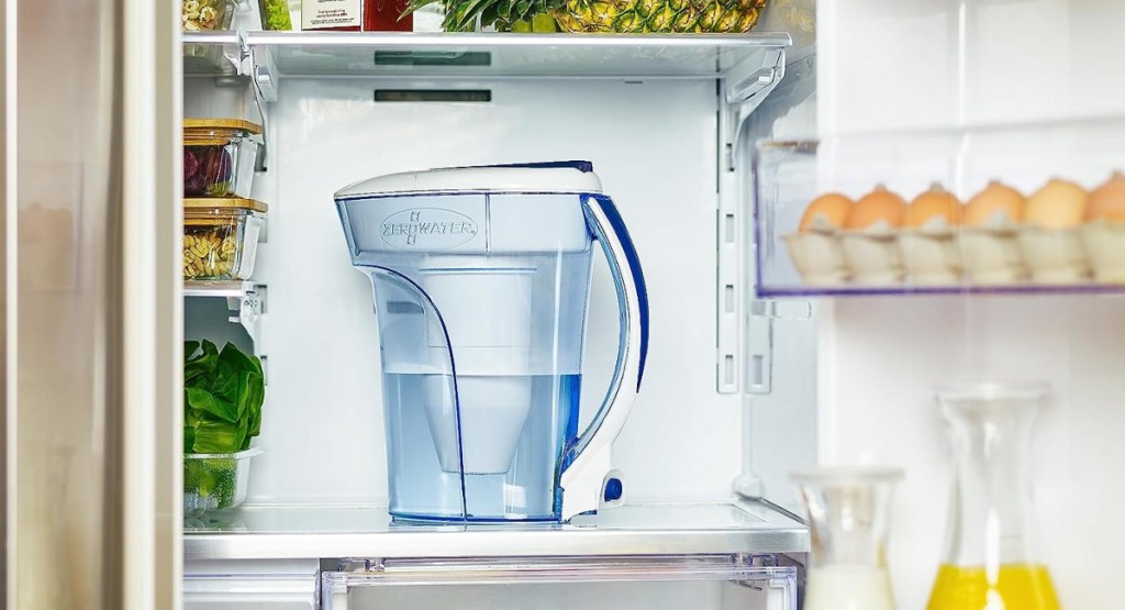 water pitcher displayed in the middle of the fridge with food around it