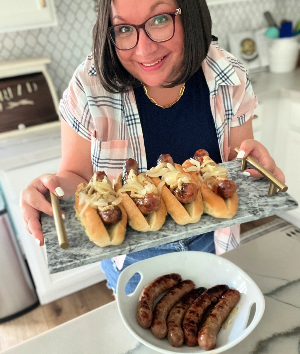 woman holding a tray of grilled brats