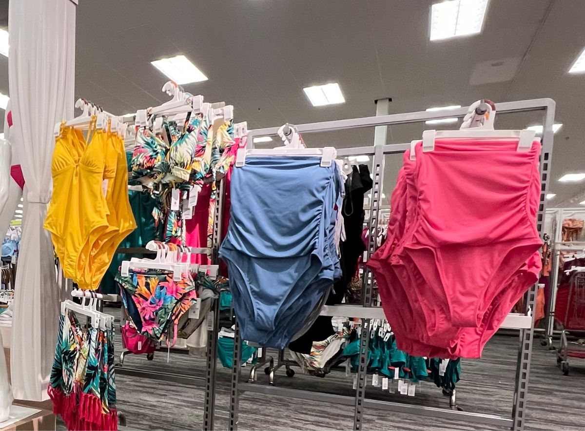 one piece swim suits in yellow blue and pink on a rack in a target store