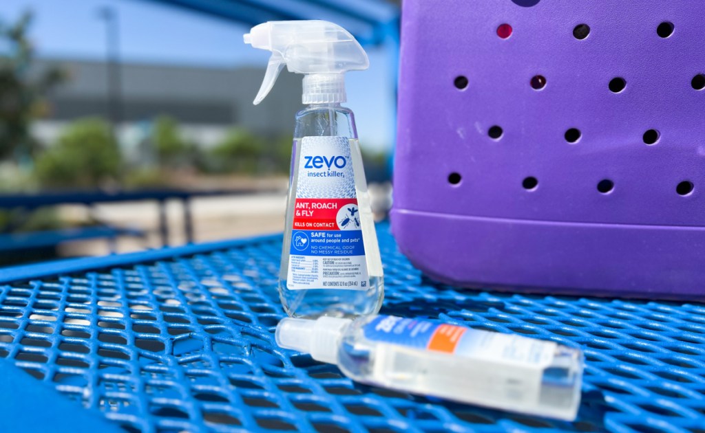 two bottles of zevo insect killer sprays near a beach bag