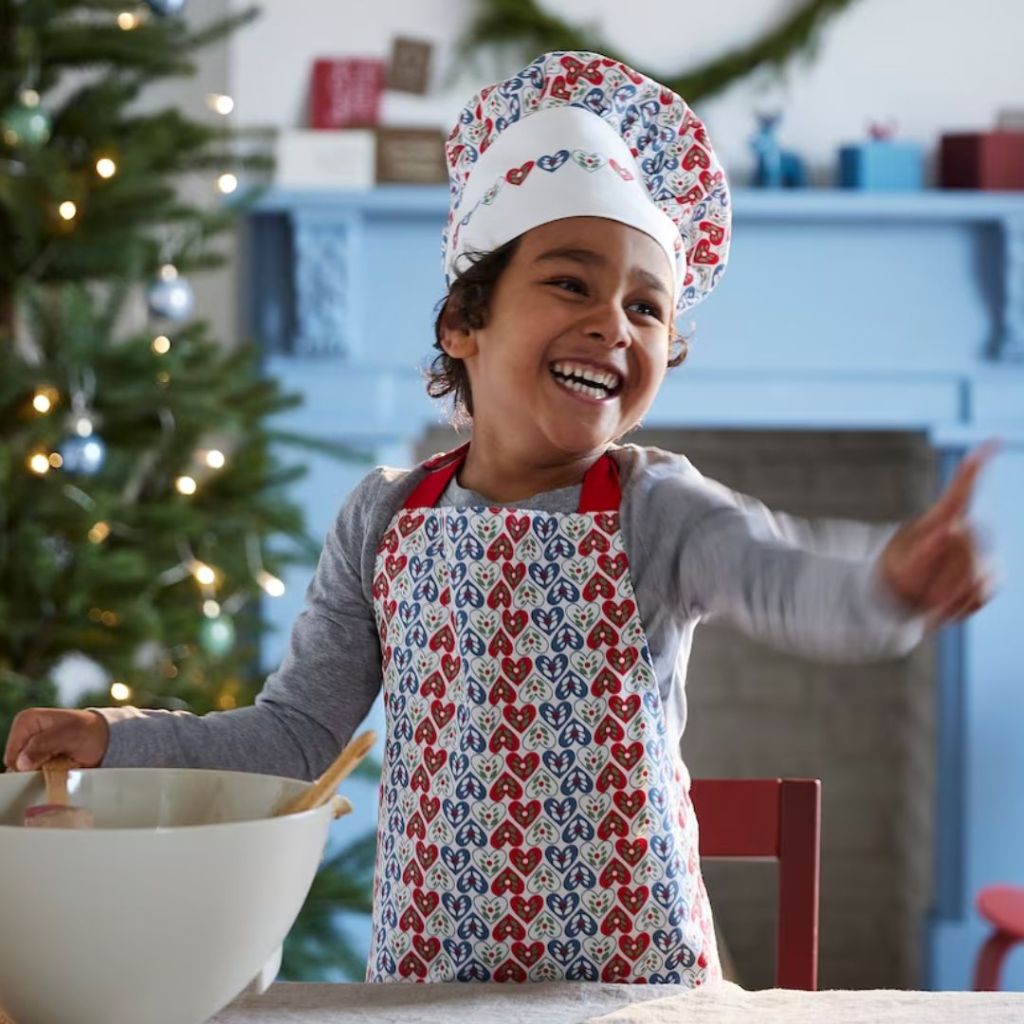 little girl wearing a red, blue and white heart Chefs Hat and Apron