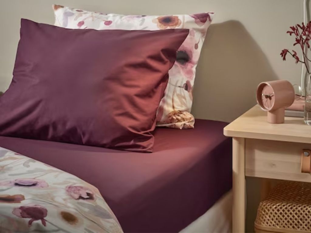 bed with purple and floral pillows, pillow cases and sheets and bedding