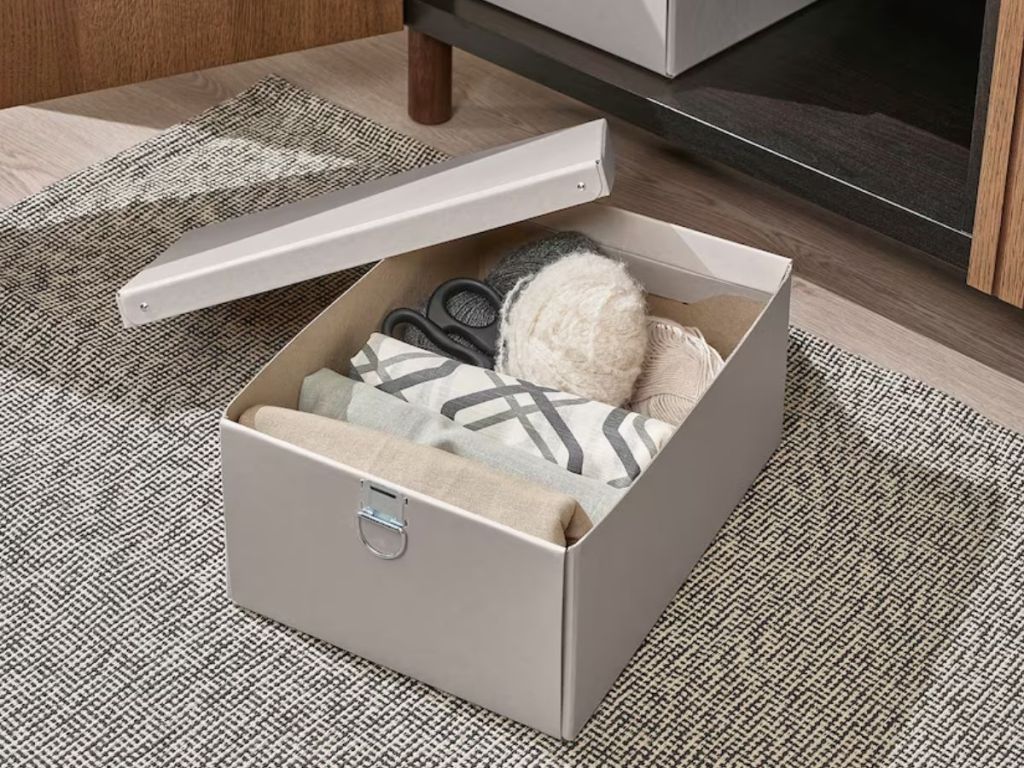 tan IKEA storage box with lid open sitting on floor