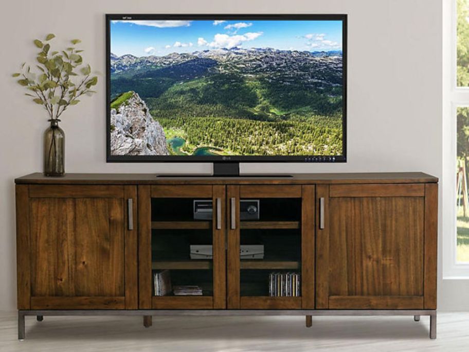 medium brown large wood media stand with large TV on it
