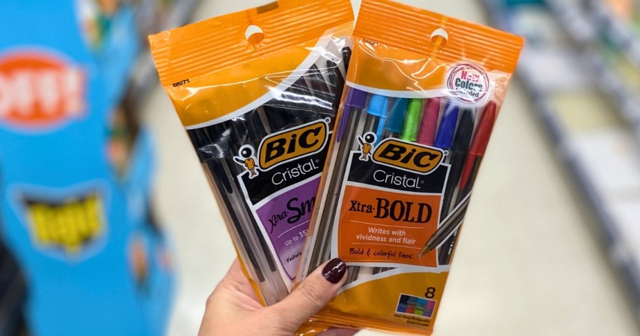 hand holding 2 packs of Bic Cristal pens in a store aisle