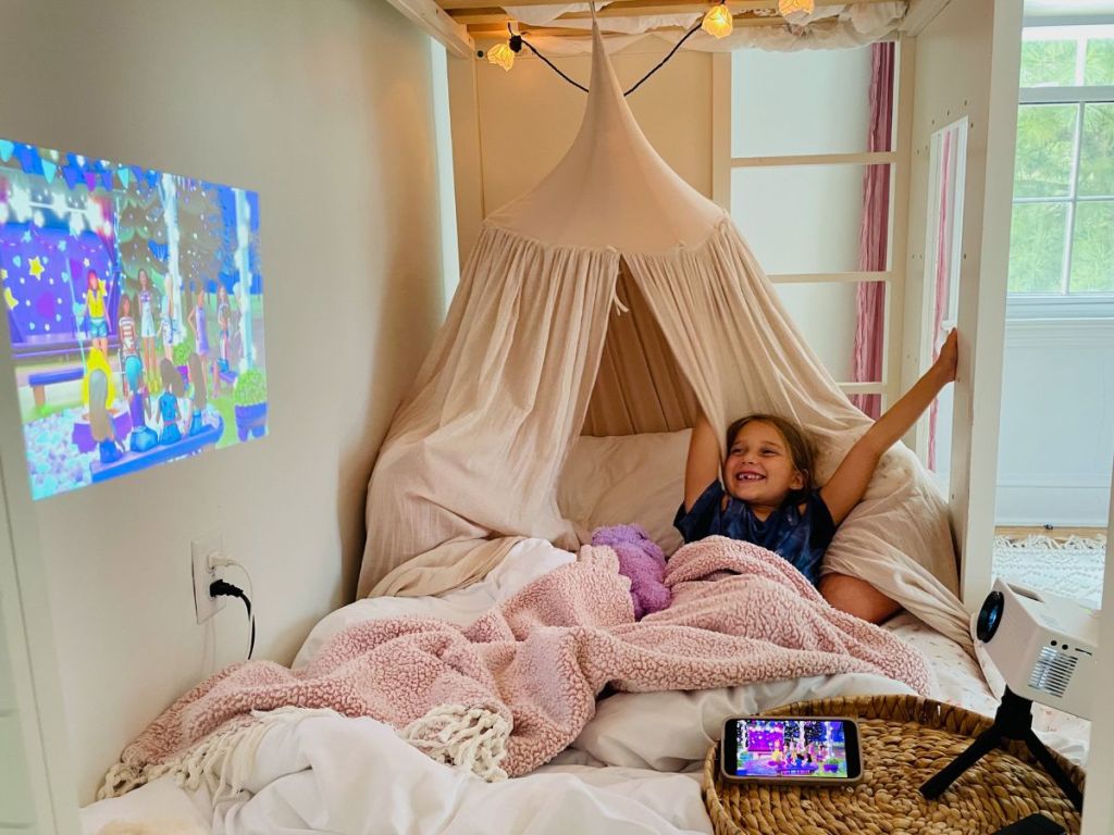 TMY Mini Projector with Tripod shown being used in little girl's room - little girl watching movie on the wall