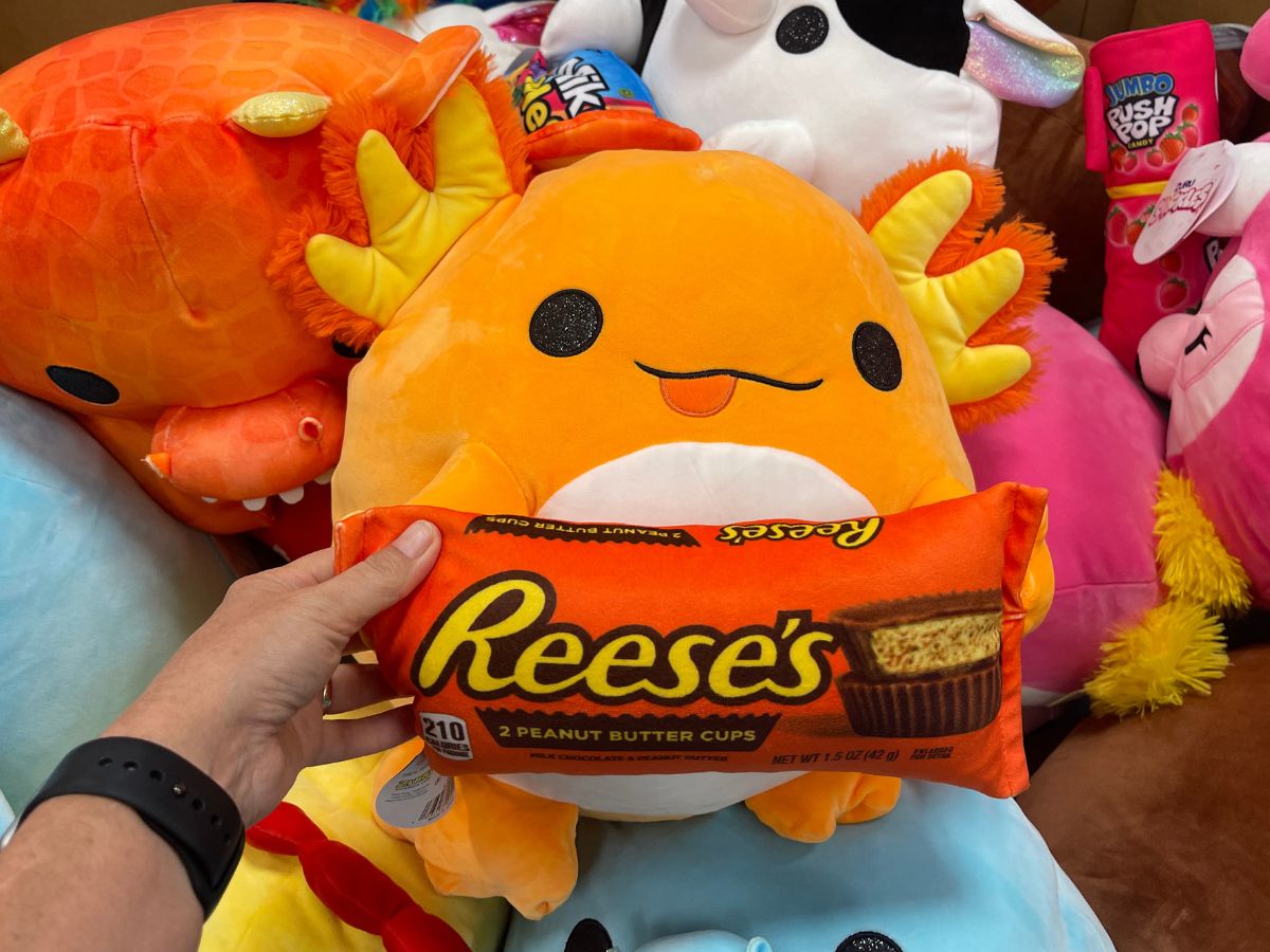 An axolotl plush toy holding Reese's Cup