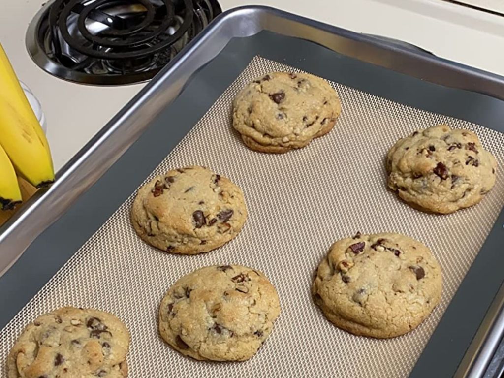 A sheet pan with an Amazon silicone baking mat on it with freshly baked chocolate chip cookies on it