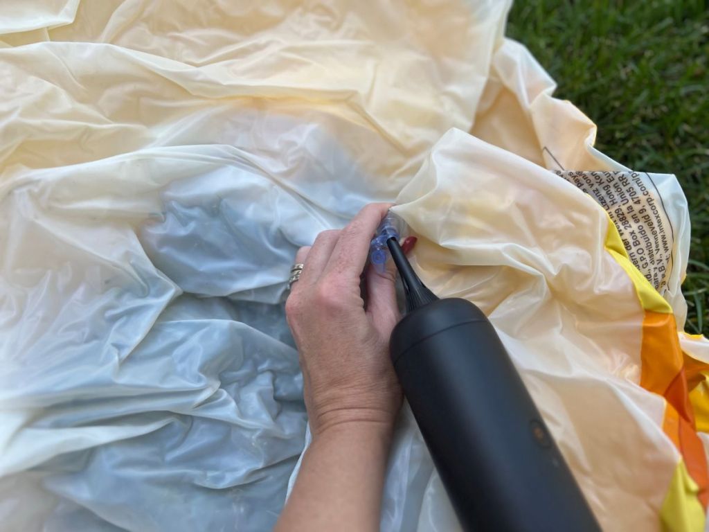 person using air pump to inflate pool float