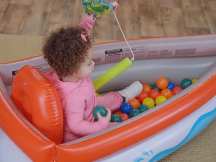 Little girl sitting in a Bass Pro inflatable ball pit