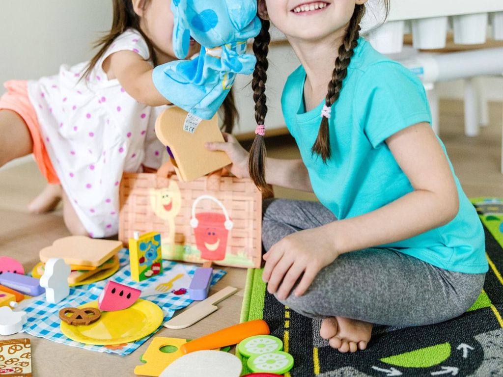 Two girls playing with a Blue's Clues picnic set indoors 
