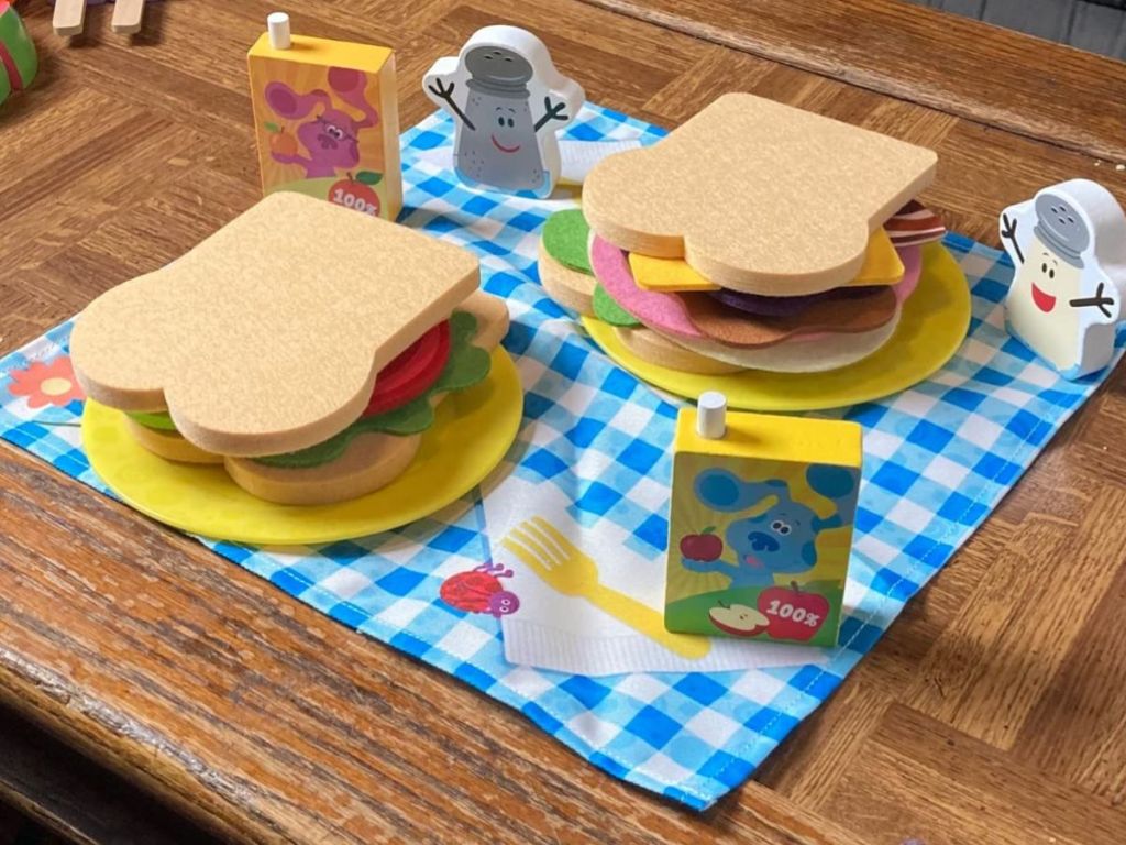A pretend picnic set on a table with sandwiches and juice boxes