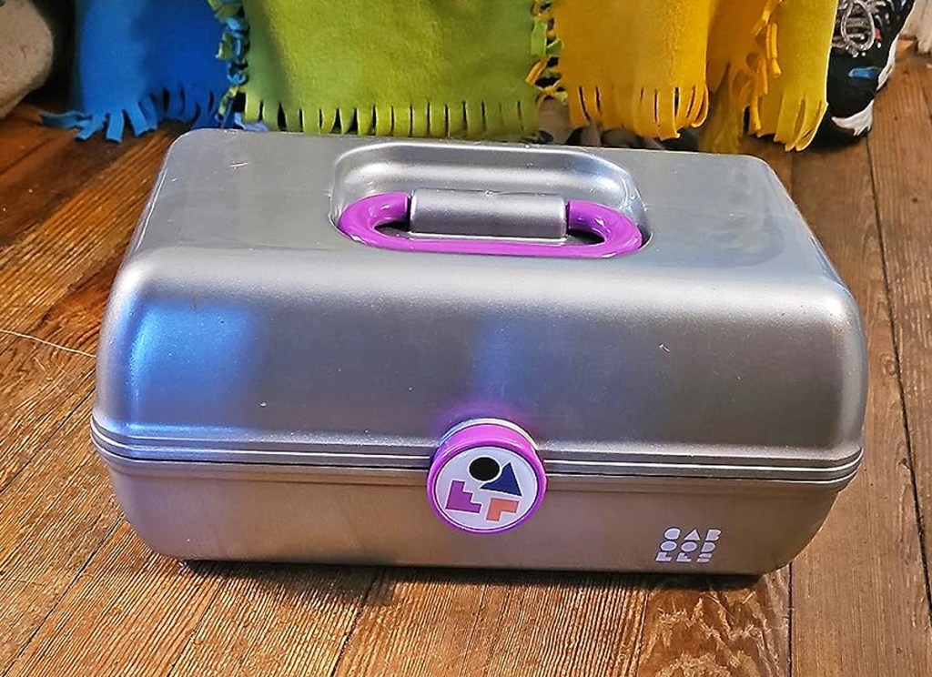 silver and purple Caboodles case on wood floor