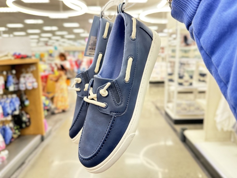 holding up a pair of blue boat shoes in store