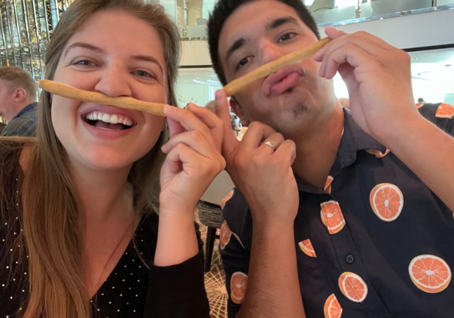 A couple dining aboard a cruise ship and playing with breadsticks