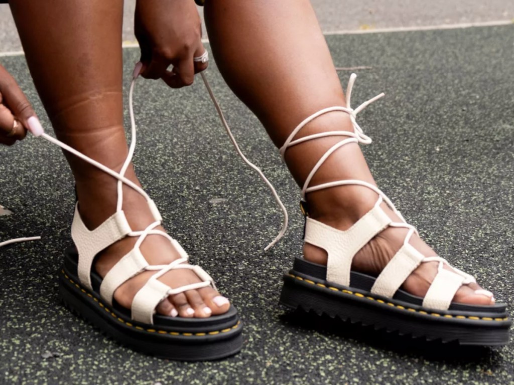 woman lacing up white Dr. Martens Gladiator Sandals
