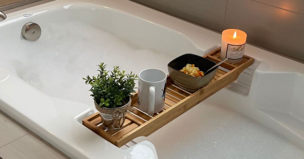 Extendable Bamboo Luxury Bath Caddy with bath, a plant, and food