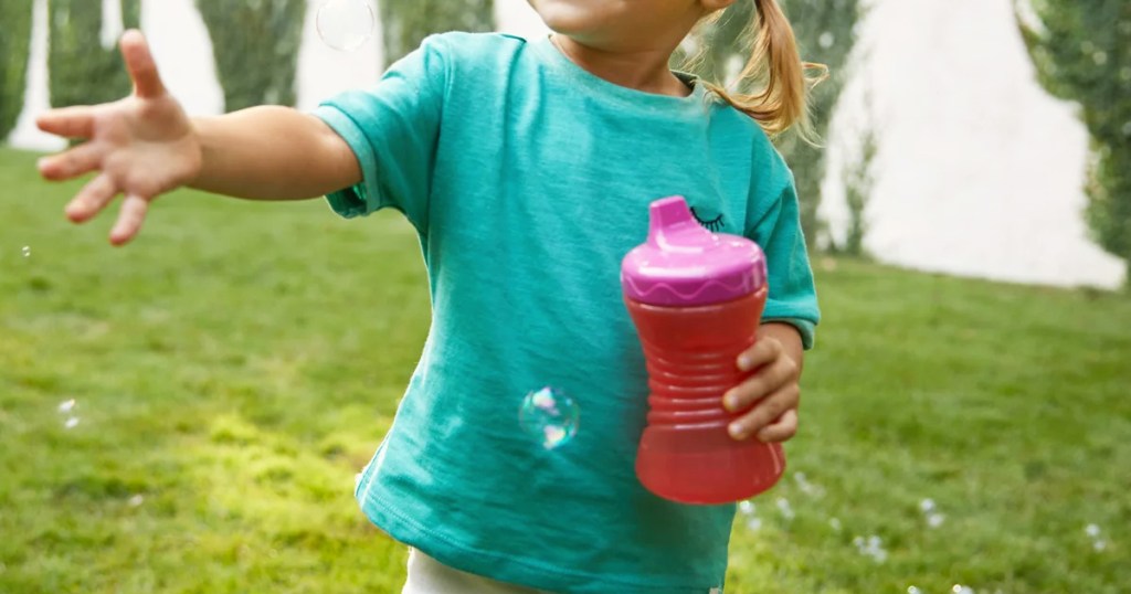 toddler in a teal t-shirt holding a pink sippy cup