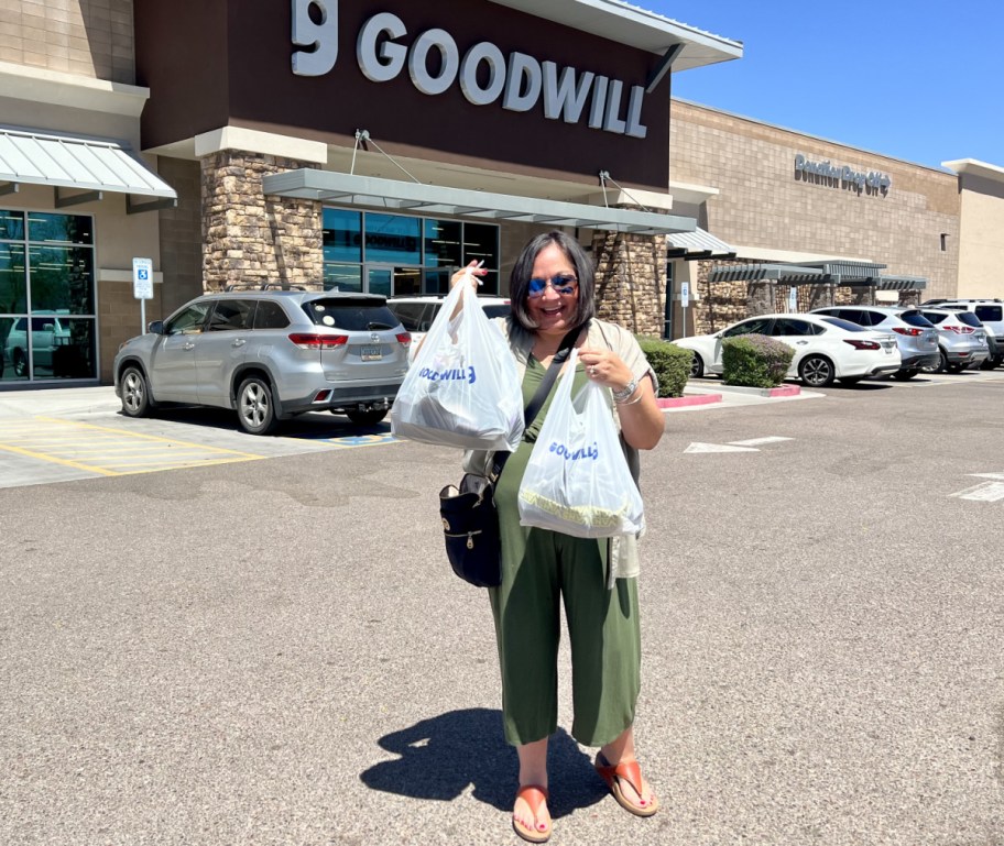 Woman holding up her Goodwill shopping haul