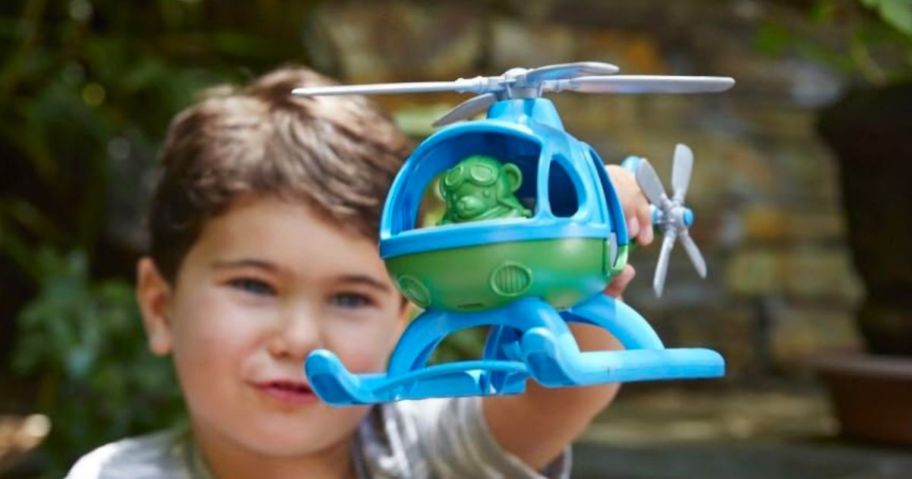 boy playing with green and blue helicopter toy