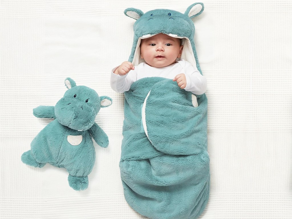 baby wrapped up in a blue hippo blanket wrap with a matching hippo toy beside them