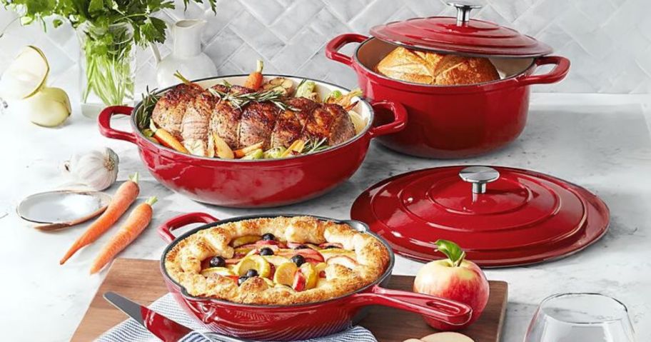 red set of cast iron enamel cookware on kitchen counter with food cooked in it 