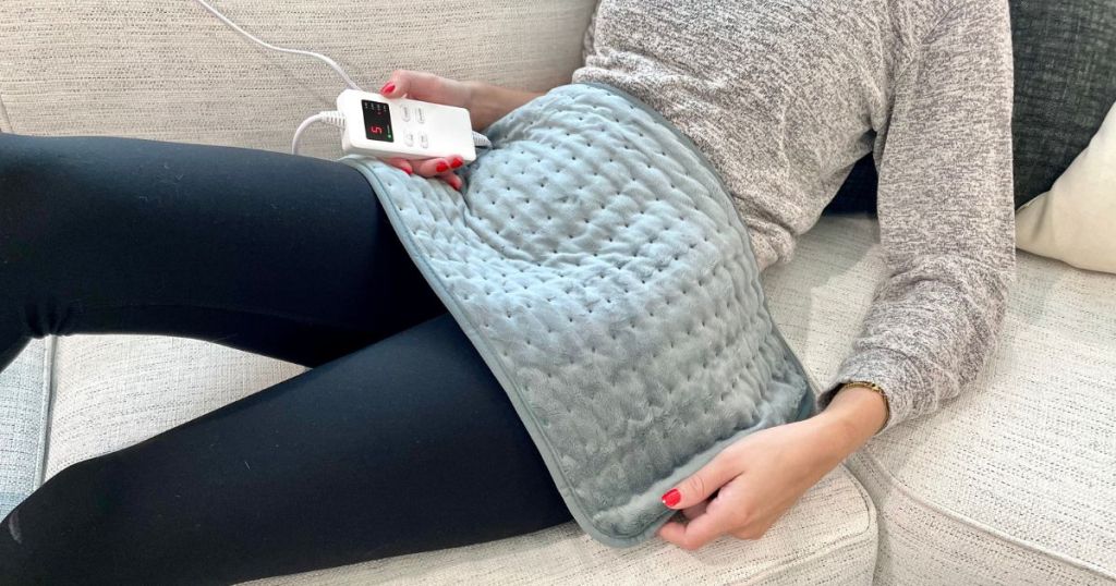 Cimoby Heating Pad shown with woman using it on her stomach while laying on the couch
