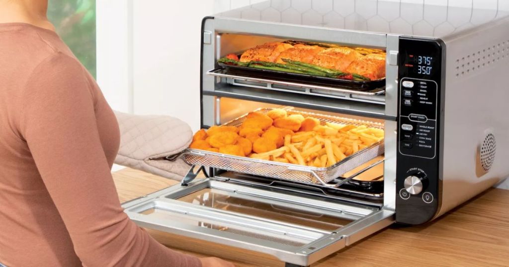 Ninja 12-in-1 Double Oven with FlexDoor shown with food inside, woman opening to pull food out
