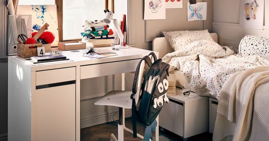 white desk and chair in room by bed