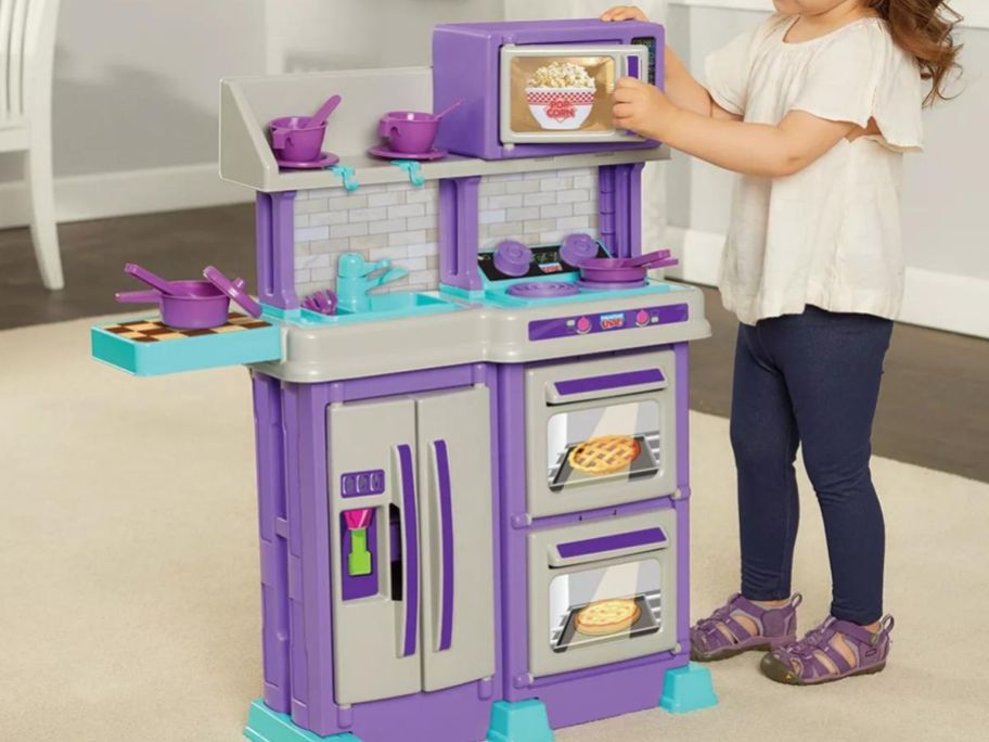 A little girl playing with a little chef play kitchen 