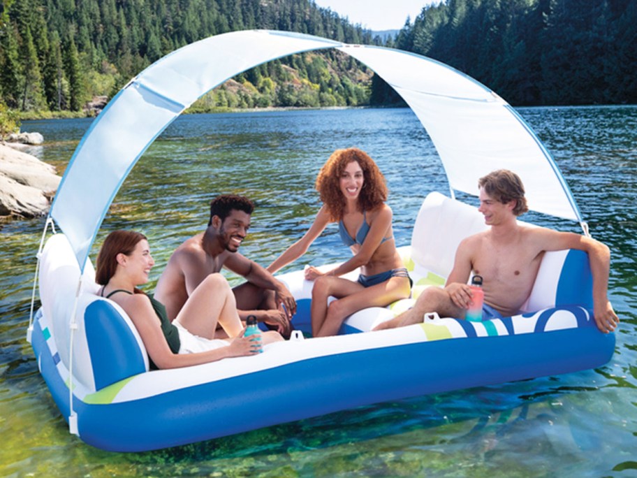 four people sitting on a white and blue float in lake