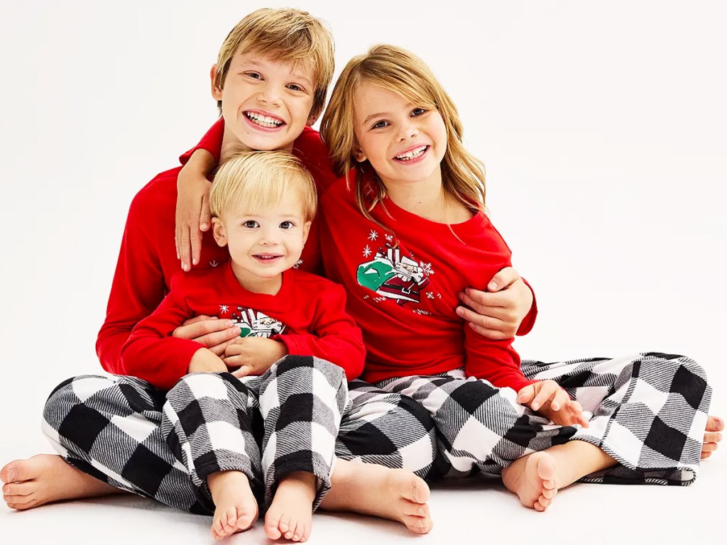 three kids wearing matching christmas pajamas