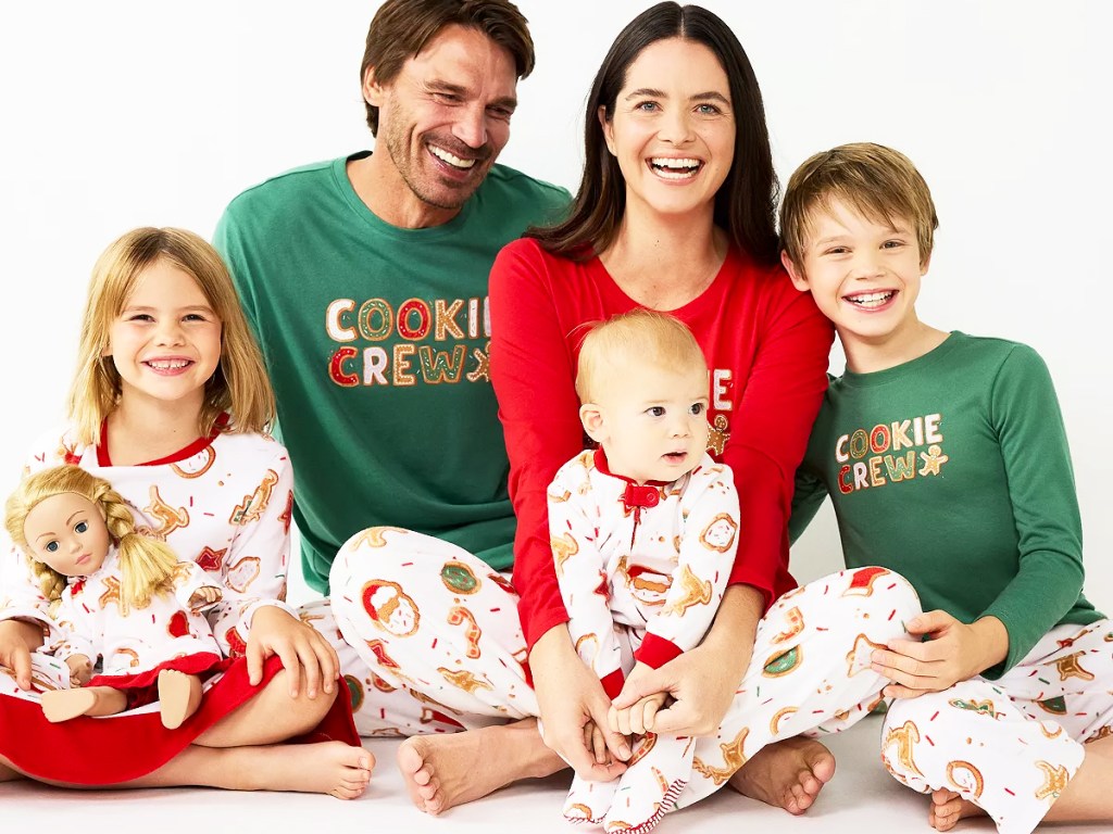 family sitting on floor wearing matching christmas pajamas