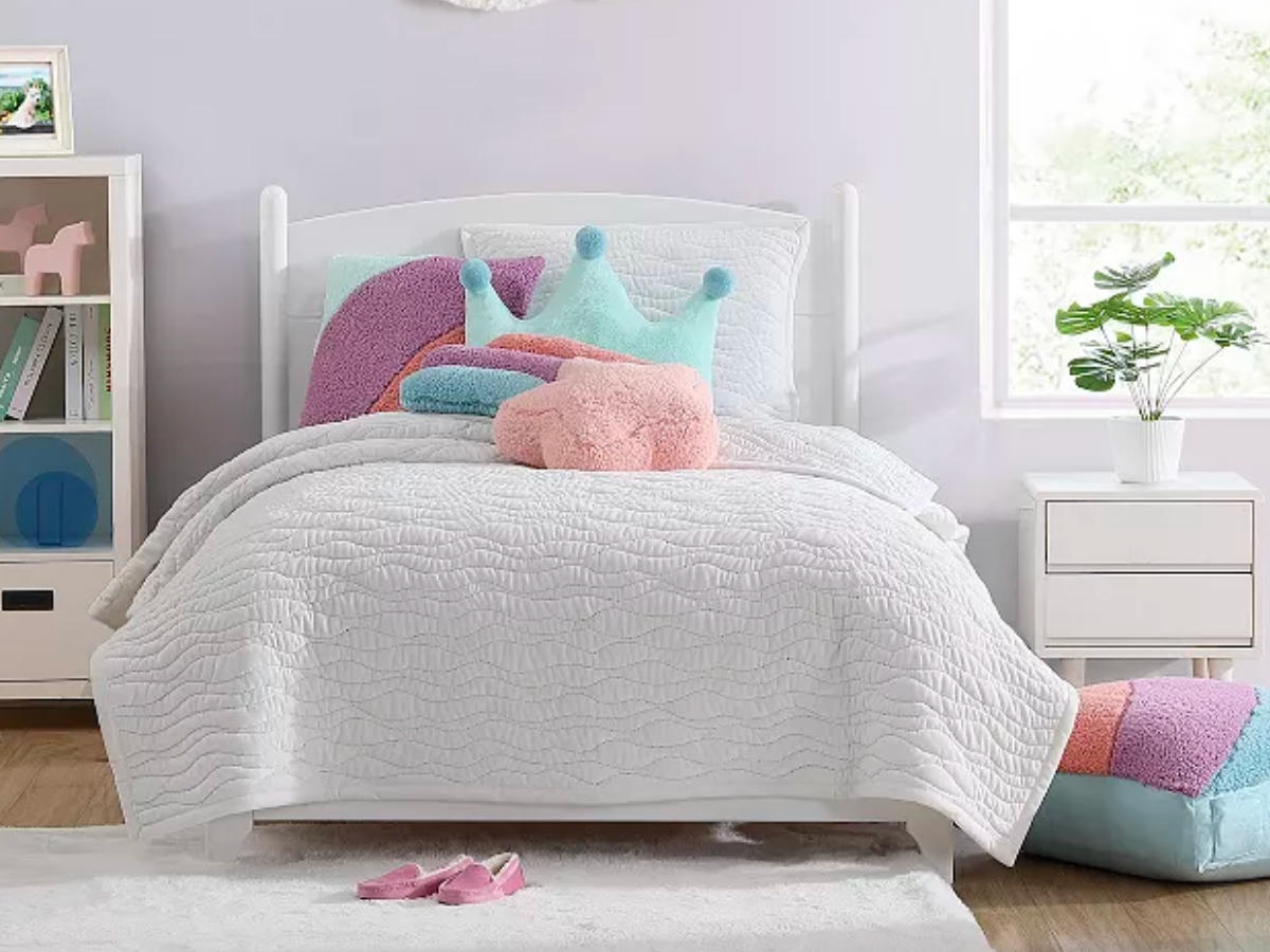 white kid's bedding set with colorful pillows in a bedroom