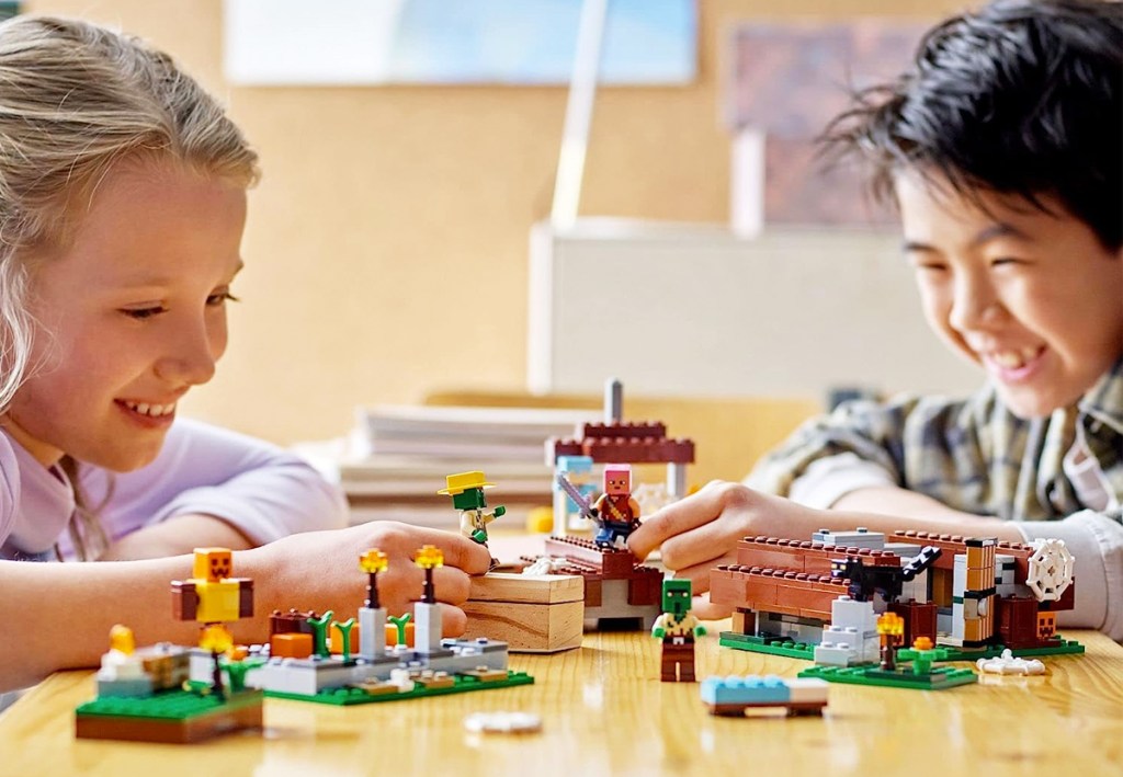 boy and girl playing with lego minecraft village set