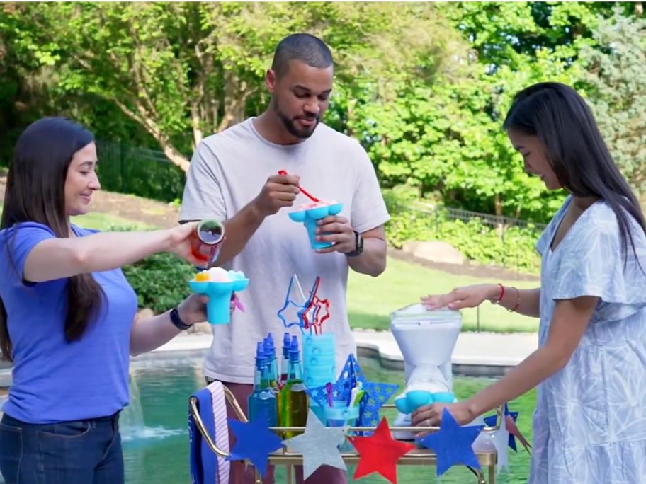 Man and two women making snow cones with a Little Snowie Max maker