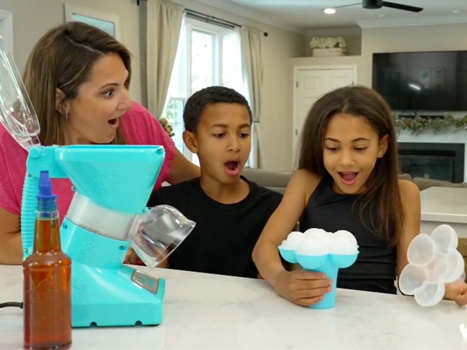 A mom and two kids very impressed with the daisy ice mold that comes with the Little Snowie Max bundle