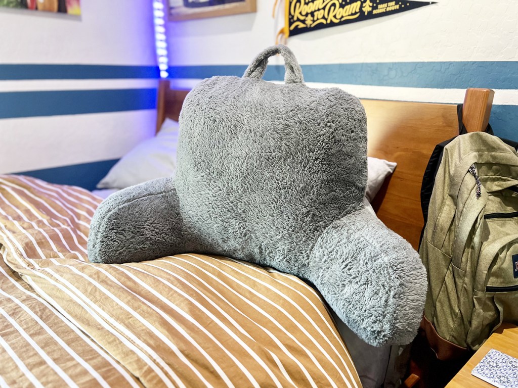 fuzzy grey bedrest pillow on a bed