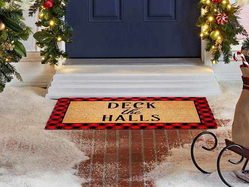 front door with doormat that says deck the halls