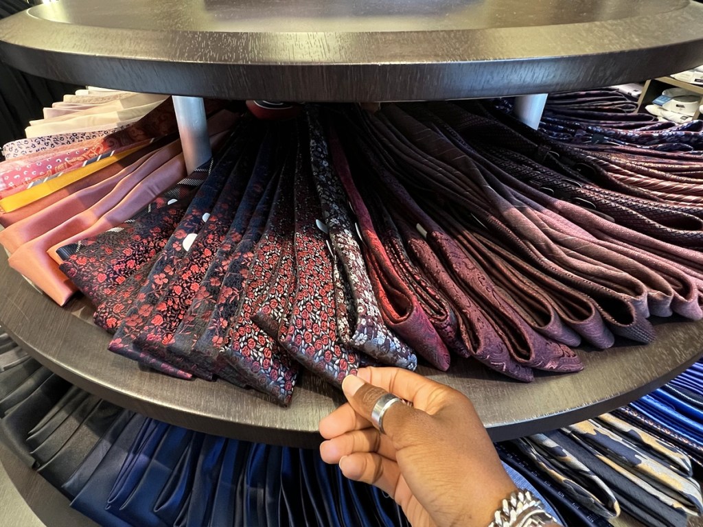 hand reaching for men's ties on a store display