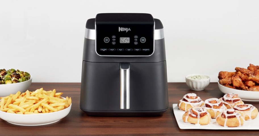 ninja air fryer on kitchen counter surrounded by plates of foods