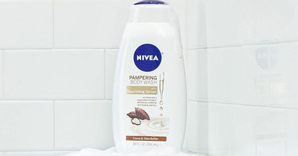 bottle of nivea pampering body wash placed on corner of bathtub with white subway tile in background