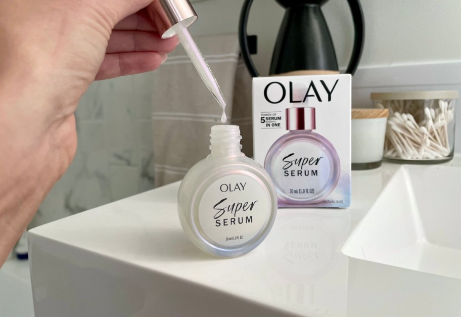 hand holding the dropper of an Olay Super Serum bottle